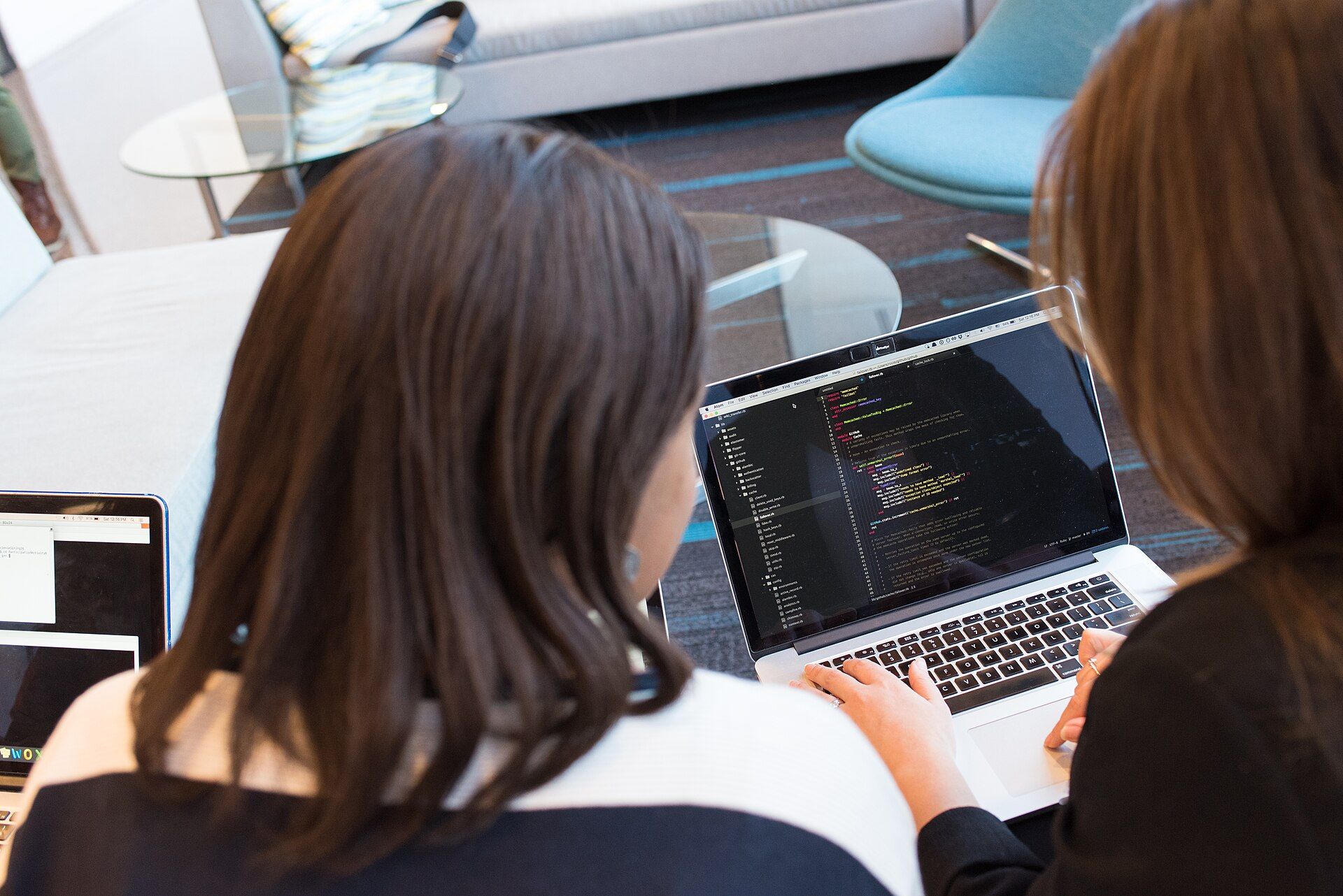 Dos mujeres revisan juntas código en la pantalla de un portátil; una escribe en el teclado